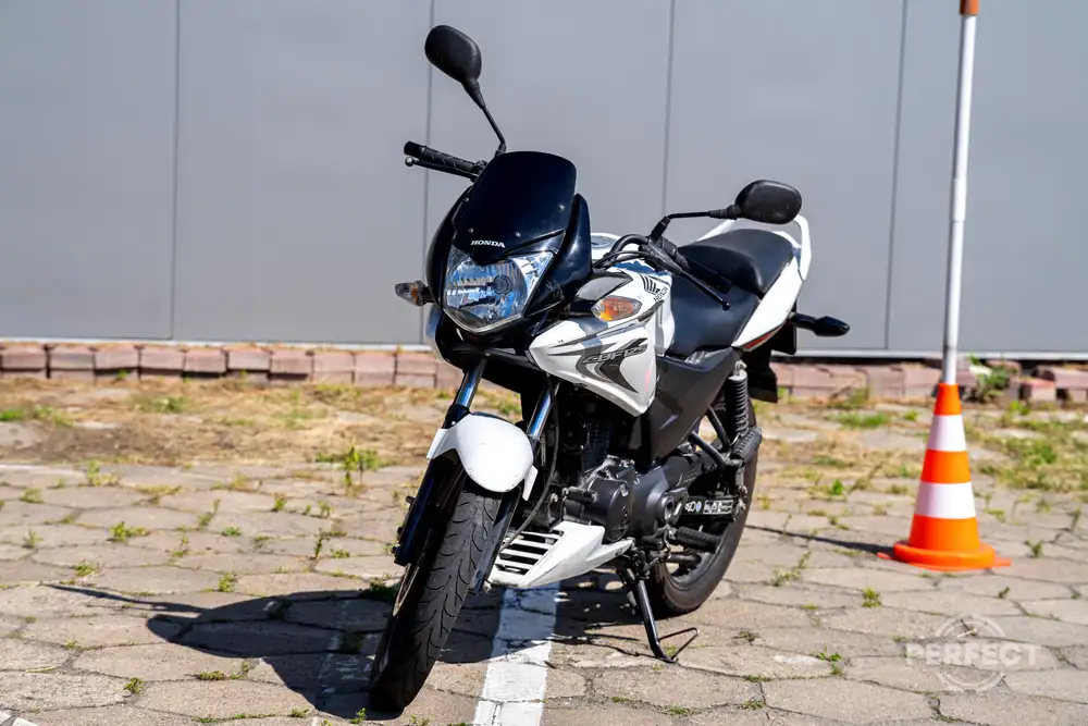 Czarny motocykl Honda CB125R na placu egzaminacyjnym WORD Zamość. Pojazd egzaminacyjny kategorii A1 z mocą 15 KM i silnikiem 125 cm³. Na zdjęciu widoczny bok i przód motocykla z charakterystycznym okrągłym reflektorem LED w stylu Neo Sports Café.